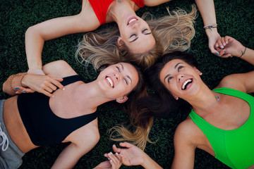 Shot of a three friends lying down on grass and smiling after training.