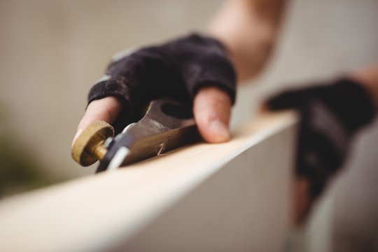 Carpenter's hand leveling a wooden frame with block plane