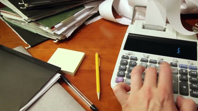 Close up of a man's hand, hard at work using a calculator.