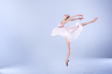 Ballet Perfection. Young and beautiful ballerina is dancing in a white studio full of light. - obrazy, fototapety, plakaty