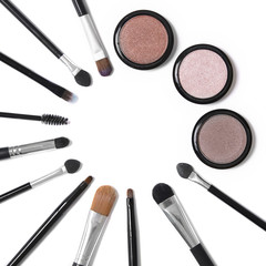 Make up brushes and eye shadows isolated on a white background, and arranged in a circle to form a page border