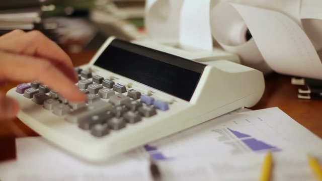 Close up of a man's hand, hard at work using a calculator.