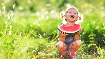 Happy child girl eats watermelon