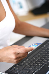 main de femme sur un ordinateur avec une carte bancaire