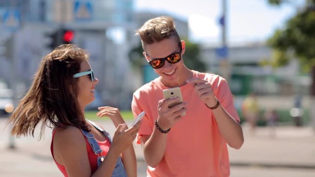 happy teenage couple with smartphones in city