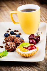 Mug of coffee and pastry on wooden background