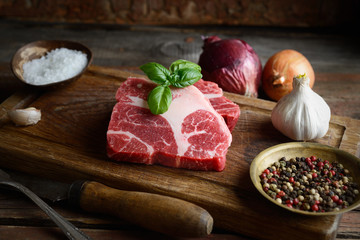 Raw marbled beef on a cutting board, onion, garlic, spices
