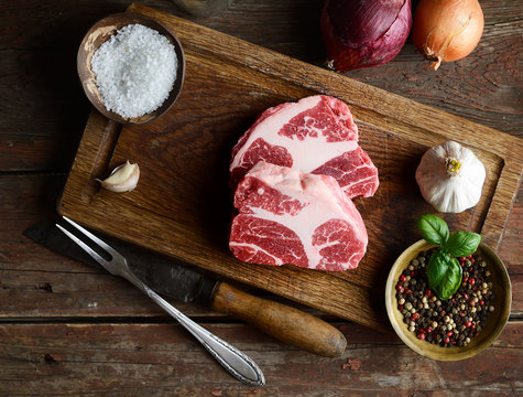 Raw marbled beef on a cutting board, onion, garlic, spices
