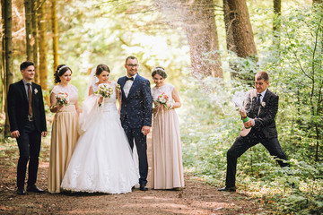 bride and groom with happy groomsmen and bridesmaids having fun and popping champagne, hilarious...