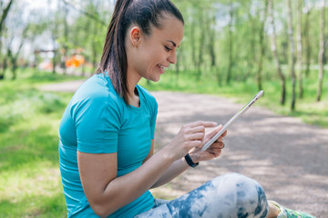 Girl is using tablet pc. She has a break in workout.