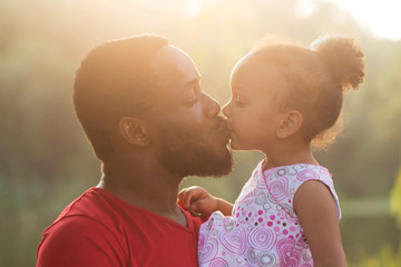 Black father kissing baby daughter