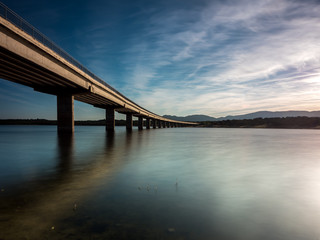 Long bridge over a lake with still water at evening