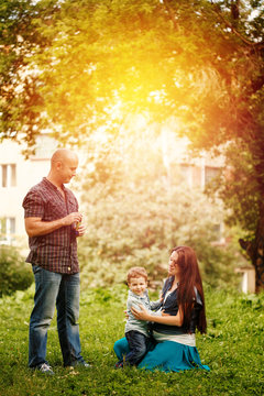 Full-body of happy family in city park at the sunset