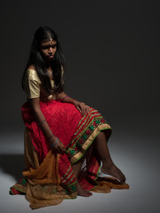 Beautiful young indian woman with long and dark hair sat wearing