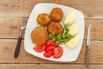 Breaded and fried meat, served with potato and tomato