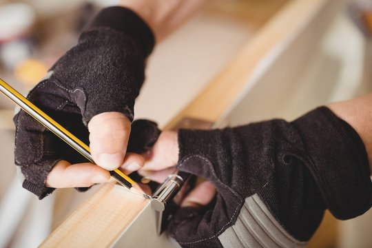 Carpenter's hands marking on door with pencil 