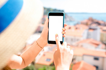 Female hands holding phone with white screen on the old city background