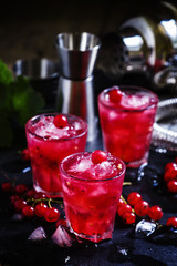 Red currant drink with ice, black background, selective focus