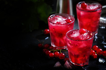 Red currant drink with ice, black background, selective focus