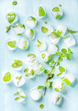 Ice Cubes With Frozen Mint Leaves Inside On Blue Turquoise Background, Top View, Vertical