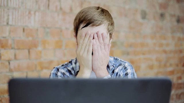 the young man in front of the laptop very upset