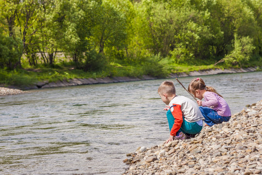 Children boy and girl playing near the river