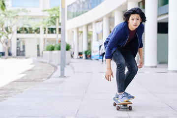 Vietnamese young guy skateboarding in the city