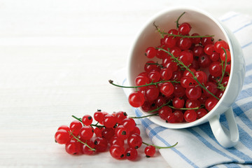 scattered red berries from a Cup on wooden background