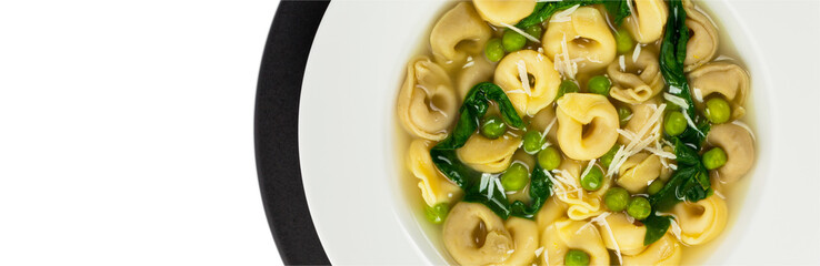 Tortellini Soup with Spinach and Peas. Panoramic image. Selective focus.