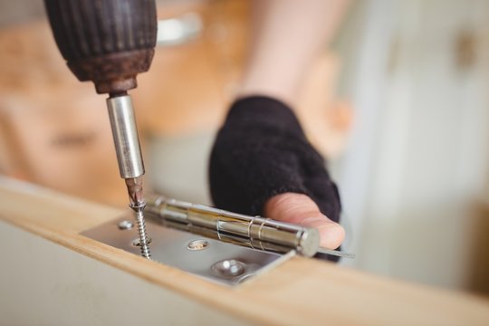 Carpenter tightening screw to hinges on a wooden door