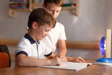 Happy little boy studying at home with brother
