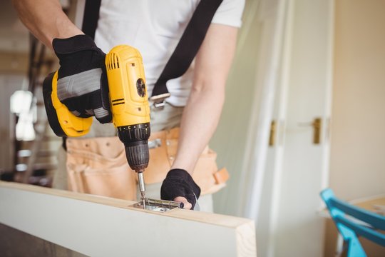 Carpenter tightening screw to hinges on a wooden door