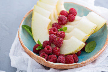 Melon slices served with raspberry and honey