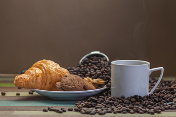 Vapor on white coffee cup with cookies and beans