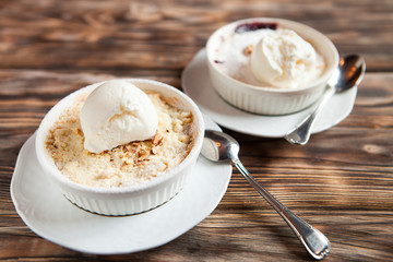 Ice cream in two white bowls on a wooden table.