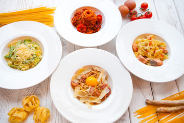 White plates with different Italian pastes decorated by ingredie