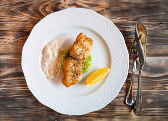 Grilled Fish with slice of lemon and white sause on wooden backg