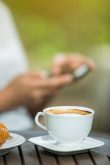 woman drinking coffee and usr smartphone in the garden