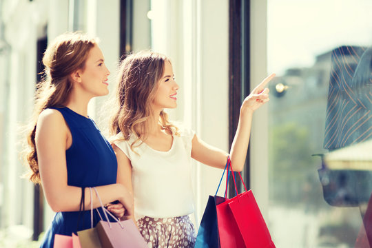 Happy Women With Shopping Bags At Shop Window