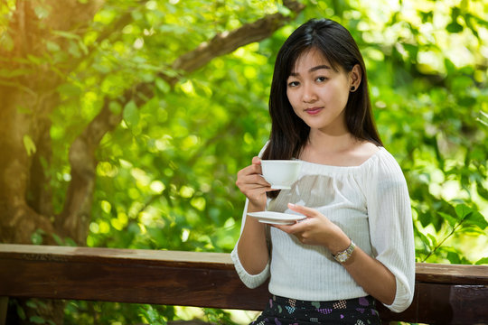 asian woman drink coffee and reading book in garden
