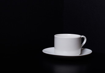 White cup and saucer on a black background