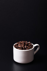 Coffee beans in the cup on black background