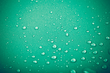 Fototapeta na wymiar Drops of water on a color background. Green. Shallow depth of fi