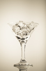 Ice cubes and martini glass on white background. Toned