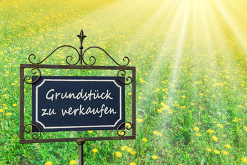 Sonnenbeschienene Wiese mit Schild „Grundstück zu verkaufen“ - Sunlit meadow with sign 
