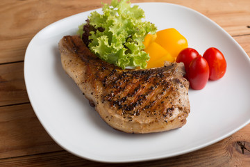Grilled Pork serve with colorful salad on wooden table