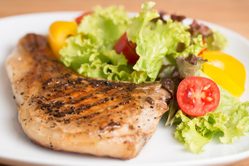 Grilled Pork serve with colorful salad on wooden table