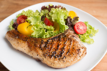 Grilled Pork serve with colorful salad on wooden table