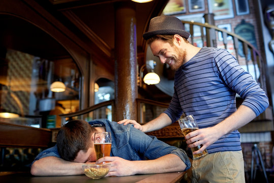 male friends drinking beer at bar or pub