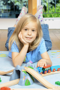 Kleines Mädchen spielt mit Holzeisenbahn in Kinderzimmer
